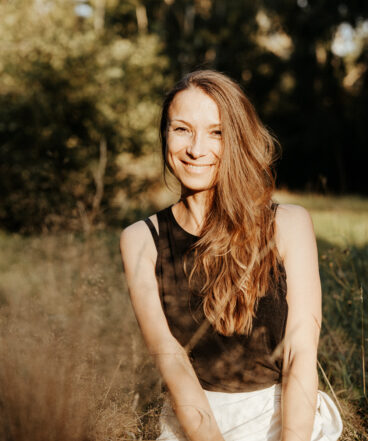 Elena, Spiritual Life Coach und Yogalehrerin, sitzt ruhig und lächelnd vor einem hellen Hintergrund. Sie steht für Achtsamkeit, Selbstliebe und ganzheitliche Begleitung mit Yoga, Meditation und Coaching.