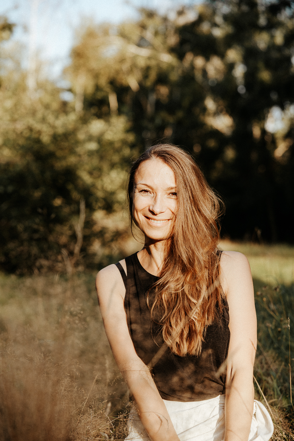 Elena, Spiritual Life Coach und Yogalehrerin, sitzt ruhig und lächelnd vor einem hellen Hintergrund. Sie steht für Achtsamkeit, Selbstliebe und ganzheitliche Begleitung mit Yoga, Meditation und Coaching.