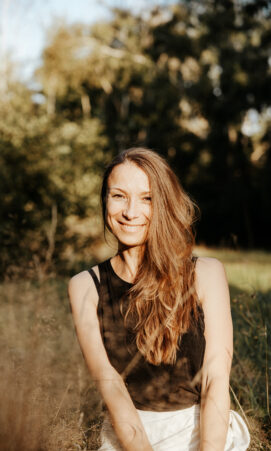 Elena, Spiritual Life Coach und Yogalehrerin, sitzt ruhig und lächelnd vor einem hellen Hintergrund. Sie steht für Achtsamkeit, Selbstliebe und ganzheitliche Begleitung mit Yoga, Meditation und Coaching.